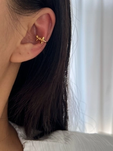 Close-up of a gold bow ear cuff in 925 sterling silver worn on the upper ear cartilage