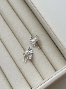 Detail view of pearl silver earrings featuring a bow and fan design in a jewelry box