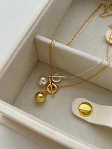 Close-up of minimalist gold and silver ball necklaces with OT clasp in jewelry box