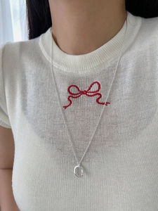 Close-up of minimalist silver horseshoe pendant necklace worn on neck with white t-shirt