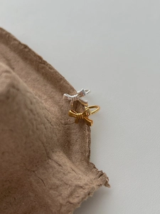 Close-up of gold and silver bow-shaped 925 sterling silver rings on textured paper