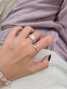 Detailed view of sterling silver ruffle ring and chunky chain bracelet on model