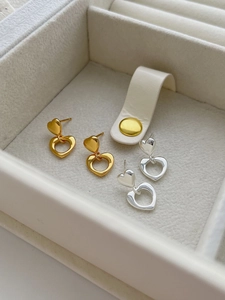 Detail of polished gold and silver heart-shaped drop earrings in a jewelry box