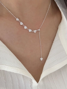 Detail shot of silver heart tassel necklace with zircon stones on a model