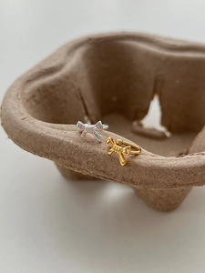 Macro detail showing gold and silver bow-shaped adjustable rings on a rustic tray