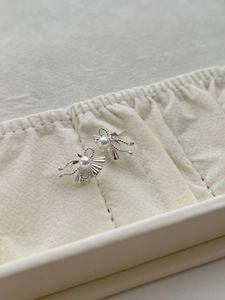 Close-up of S925 silver fan-shaped pearl earrings with bow detail in a velvet jewelry box