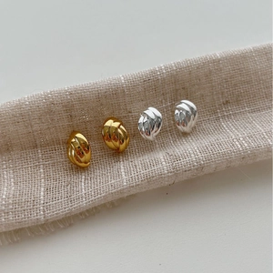 Boucles d'oreilles nœuds minimalistes dorées et argentées sur support en lin texturé