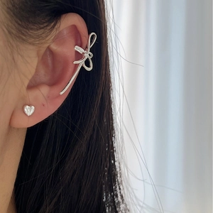 Ensemble de bague d'oreille nœud argenté et puce cœur porté par une femme