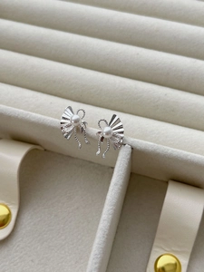 Detailed close-up of fan-shaped silver pearl earrings with fine textured radial folds