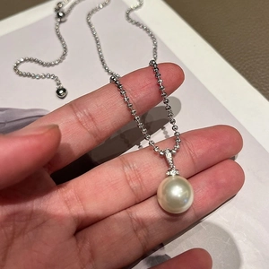 Single large white pearl pendant on silver bead chain held in hand for scale
