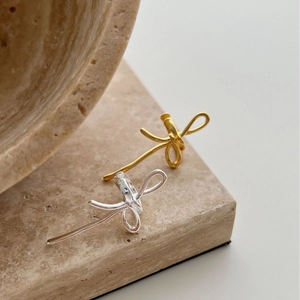 Élégantes boucles d'oreilles nœud or et argent sans perçage sur fond de pierre naturelle