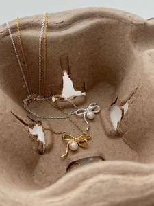 Vue macro de pendentifs nœuds en argent et or avec perles sur fond texturé élégant