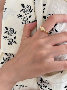 Detailed close-up of a gold bear-shaped open ring with a beaded band on model's finger