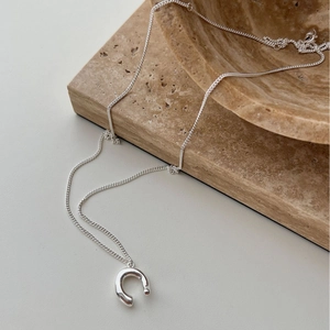 Elegant silver horseshoe pendant necklace on textured stone base for minimalist look