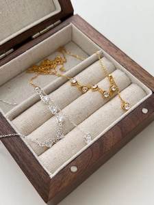 Detail of gold and silver heart necklaces with zircon stones in a wooden gift box