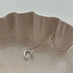 Minimalist silver C-shaped pendant necklace with polished mirror finish and thin cross chain