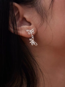 Detail of silver S925 ribbon bow earrings worn by model showcasing refined polish