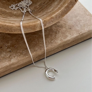 Elegant silver horseshoe pendant necklace on natural stone display for women