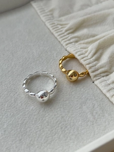 Detailed view of adjustable gold and silver ball rings on a soft neutral fabric