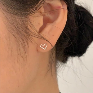 Gros plan sur une boucle d'oreille cœur évidée en argent sterling S925 sur l'oreille