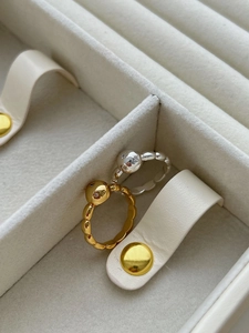 Detailed view of minimalist gold and silver ball rings on a premium white jewelry box
