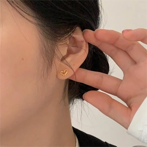 Vue détaillée d'élégantes boucles d'oreilles cœur en or portées par un mannequin chic