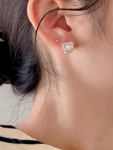 Close-up of geometric silver earring with freshwater pearl on model for vintage French style