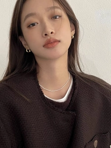 Détail de boucles d'oreilles en argent 925 doré et collier de perles sur un modèle