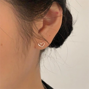 Gros plan d'une boucle d'oreille cœur en argent minimaliste au design croisé