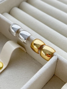Close-up of chunky gold and silver C-shaped hoop earrings in a velvet jewelry box