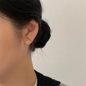 Gros plan de boucles d'oreilles cœurs évidés minimalistes portées par un mannequin
