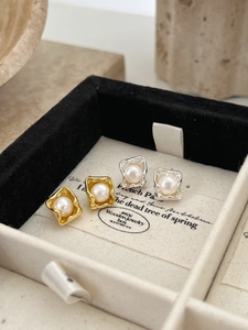 Close-up of gold and silver square metal earrings with white freshwater pearl inlays