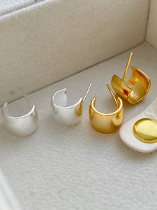 Macro shot of minimalist C-shape hoop earrings in polished gold and silver finishes