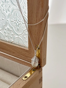 Macro shot of an acorn-shaped freshwater pearl pendant on a silver water wave chain