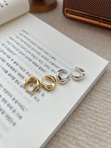 Détail de boucles d'oreilles créoles en forme de U en argent S925 doré et argenté sur un livre