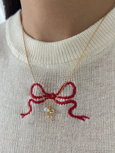 Detailed view of gold bow necklace with moonstone gemstone worn on a model neckline