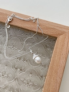 Close-up of a 925 sterling silver necklace with a luminous teardrop pearl pendant
