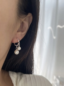 Dettaglio di orecchini pendenti con perle in argento 925 su sfondo plissettato