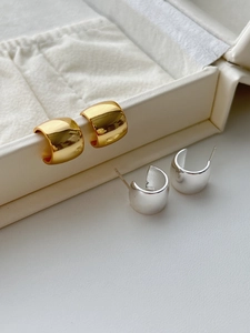 Close-up of minimalist gold and silver C-shaped chunky hoop earrings with mirror finish
