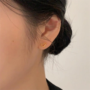 Gros plan d'une boucle d'oreille cœur dorée portée par un mannequin pour un style doux