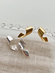 Detailed view of twisted S925 sterling silver ribbon earrings in gold and silver finish