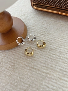 Gros plan de boucles d'oreilles créoles en U dorées et argentées sur tissu polaire