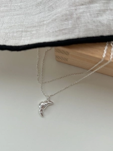 Detail of 925 sterling silver croissant pendant with polished spiral texture on a thin chain