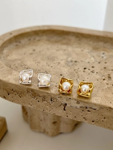 Macro shot of 925 silver and gold square frame stud earrings with freshwater pearls