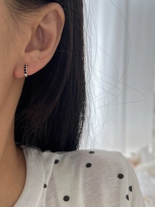 Close-up of minimalist S925 sterling silver hoop earring with three black gemstones