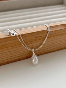 Macro shot of 925 sterling silver stamp on the water wave chain with drop pearl pendant