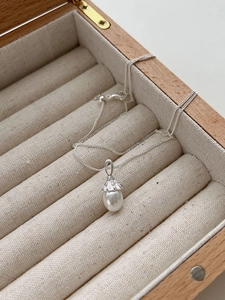 Macro shot of an acorn-shaped freshwater pearl pendant on a 925 silver wave chain