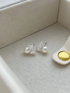 Macro shot of 925 sterling silver bow earrings with round white pearls and zircon accents