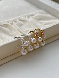Dettaglio di orecchini pendenti in argento 925 con perle su un portagioie in pelle crema