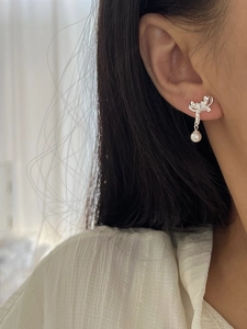 Macro view of S925 silver bow stud earrings with zircon and white hanging pearls
